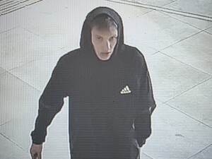 Na zdjęciu młody mężczyzna w ciemnej bluzie z kapturem na głowie, krótkich spodenkach i obuwiu sportowym