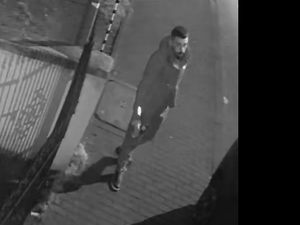 Na zdjęciu mężczyzna stojący nocą przy bramie