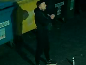 Na zdjęciu mężczyzna stojący nocą przy kontenerach na śmieci