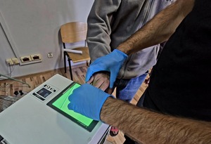 Technik kryminalistyki pobiera odciski palców zatrzymanemu.