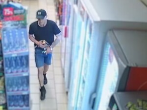 Młody chłopak w czapce bejsbolowej, koszulce z krótkim rękawem i krótkich spodenkach robi zakupy w sklepie samoobsługowym