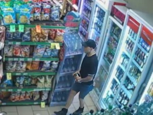 Młody chłopak w czapce bejsbolowej, koszulce z krótkim rękawem i krótkich spodenkach robi zakupy w sklepie samoobsługowym
