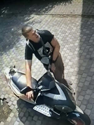Na zdjęciu młody chłopak w ciemnej koszulce i długich spodniach, prowadzący motorower.