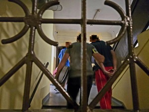 Widok zza krat-policjanci prowadza zatrzymanego