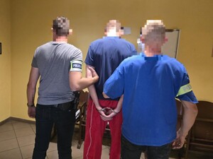 Dwóch nieumundurowanych policjantów prowadzi zatrzymanego