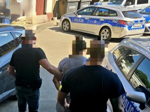 Policjanci prowadzą zatrzymanego do radiowozu
