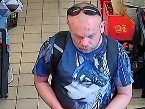 Na zdjęciu mężczyzna w średnim wieku z okularami na głowie. W koszulce niebieskiej i z plecakiem na plecach.