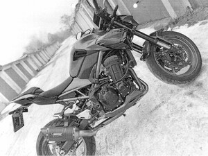 Motocykl stoi na śniegu pomiędzy garażami