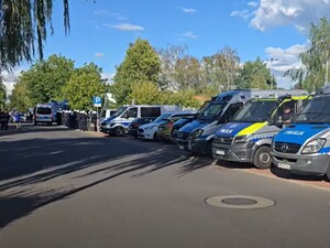 wzdłuż ogrodzenia stoją radiowozy policyjne podczas zabezpieczenia meczu