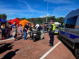 Radiowóz- pojazd wypadkowy, motocykl i policjant podczas dni otwartych zajezdni PKM. Grupa ludzi oczekuje w tle na możliwość skorzystania z atrakcji.